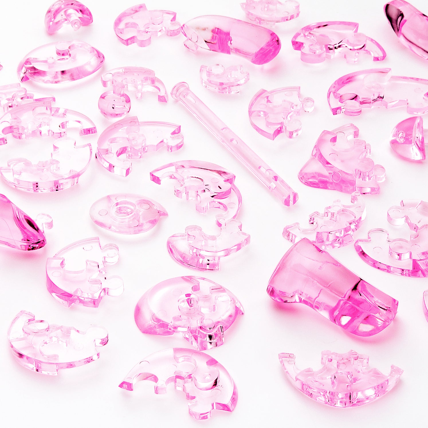 Pink pieces of 3D Crystal Puzzle bear scattered on a white background.